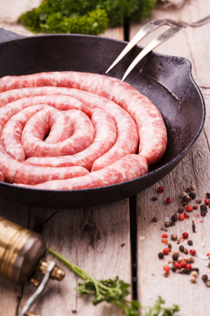 Sausages raw homemade frying in a cast iron skillet,composition spiral.selective focusの写真素材