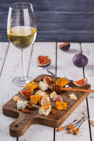 Grape, cheese, figs and honey with a glasses of red and white wine on a wooden Board. Cheese Board.selective focusの写真素材