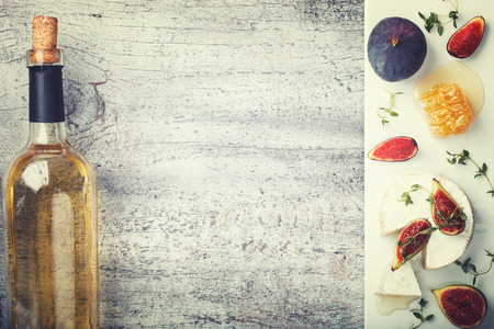 Cheese Board,appetizer.Brie cheese,Camembert,bottle of white wine,figs,honey and thyme and white wine.Copy space. Toned image. Vintage style.selective focusの写真素材