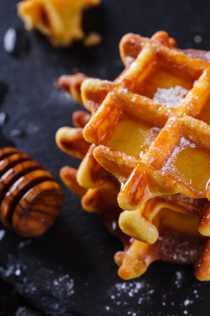 Belgian waffles with honey on a black background.の写真素材
