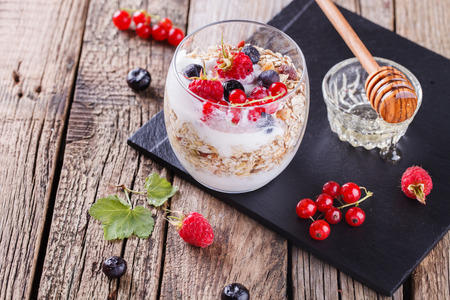 Breakfast with muesli, yogurt,honey and fresh berries in a glass on a wooden background. selective focusの写真素材