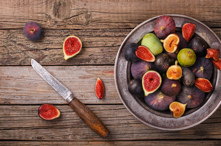 Fresh figs in different grade, in a vintage metal plate on a wooden Board.selective focusの写真素材