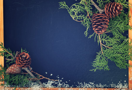 Christmas and new year decorations.Dark Board text.Branches of fir cones,white snow.Copy space.Toned...