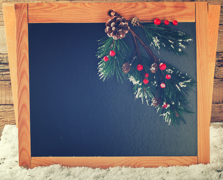 Christmas and new year decorations.Dark Board text.Branches of fir cones,white snow.Copy space.Toned image.Vintage style.selective focus.の写真素材