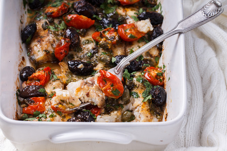 Baked fish in a ceramic form with black olives,tomatoes,lemons and herbs.selective focusの写真素材