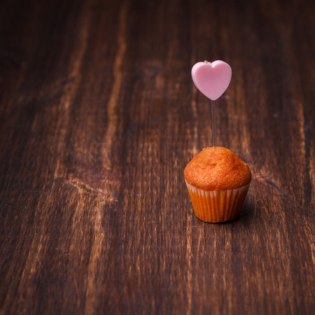Mini muffin with a candle in the shape of a heart.の写真素材
