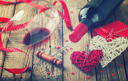 Gift , the heart and the bottle of red wine for a romantic holiday Valentine's day on vintage wooden background.Toned image.Vintage style.selective focus.の写真素材