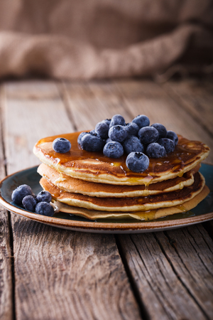 Pancake folded stack of with liquid honey and fresh blueberries on wooden background.の写真素材