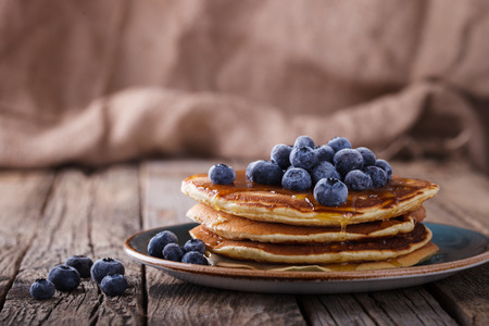Pancake folded stack of with liquid honey and fresh blueberries on wooden background.の写真素材