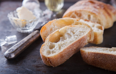 Italian ciabatta bread cut in slices on chopping board with butter,olive oil and salt.selective...
