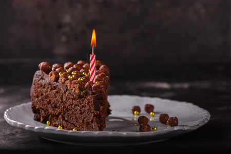 Piece of chocolate cake with candle on a dark background.selective focus.の写真素材