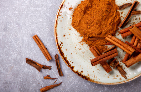 Cinnamon sticks and cinnamon powder on the plate.の写真素材