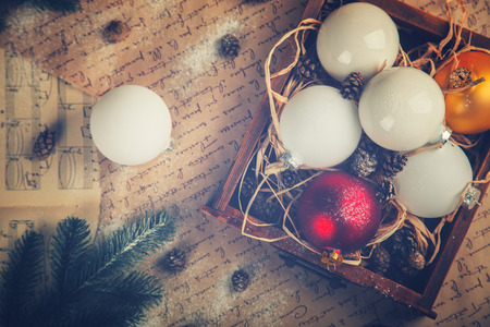 Vintage wooden box with Christmas Toys, Decorations. Holiday Postcard. Snow Drawn.Balls,Cones on aged Background.Toned image.Vintage style. selective focus.の写真素材