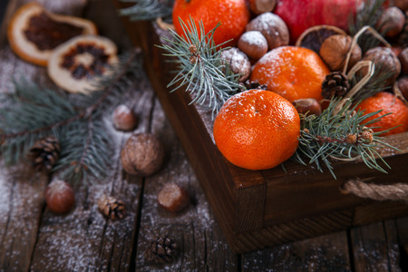 Christmas New Year  card. Tangerines,Nuts,Pomegranate,Citrus,Tree Branches  in a wooden box.Festive Background.Vintage style.selective focus.の写真素材