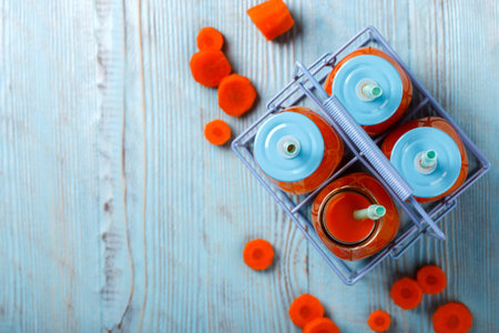 Fresh Carrot juice in a bottles on wooden background. Healthy food or diet concept.の写真素材