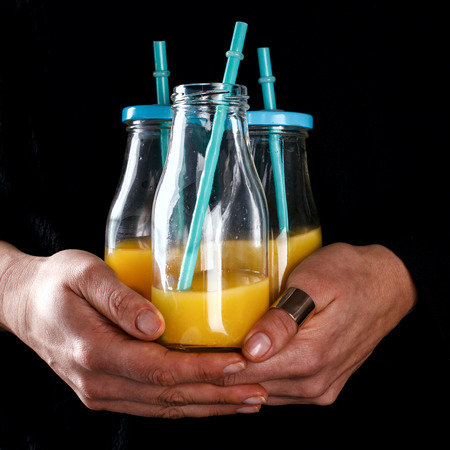 Orange juice in the Hands of a woman in a Glass bottle..Food or Healthy diet ?oncept.selective focus.の写真素材