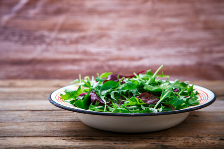 Fresh Green Mix Salad on Vintage Wooden background in a metal bowl.Leaves Of Spinach,Arugula,Romaine,Lettuce.Concept of Healthy Food.Copy space for Text. selective focus.の写真素材