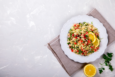 Tabbouleh salad with couscous on the plate.Traditional middle eastern or arab dish.Vegetarian.Parsley,pepper,cucumber,tomato,lemon.Middle eastern meze.Food or Healthy diet concept.Copy space for Text.の写真素材