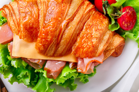 Fresh Croissant Sandwich with  Ham, Cheese,Cherry tomatoes and Salad leaf  on the Tray with  a glass of Juice Orange  Breakfast in bed Delicious Baking  Light Mealの写真素材