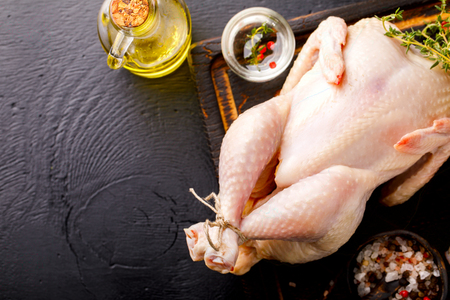 Whole Raw Chicken with Herbs and Spices on Wooden Cutting Board Food Ingredient Cooking Background Bird Meat Copy space for Textの写真素材