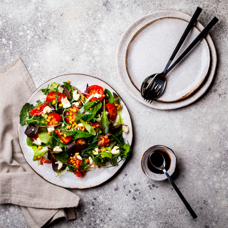 Salad Mix  Greenery Cherry tomatoes Nuts and Cheese on a Plate and Stone Background with Vegetarian Sauce Food or Healthy diet concept Super Food Vegetarian Top View Copy space for Textの写真素材