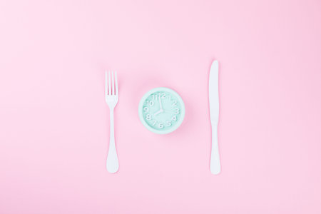 Concept minimal Time to Eat. Alarm Clock  on a pink pastel Background. Top View. Flat Lay. Copy...