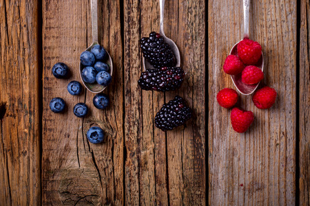 Berries on a vintage spoon on the Old Wooden Background.Blueberries, Raspberry, Strawberry Summer Vitamins. Top View.Copy space for Text. Healthy Food.の写真素材