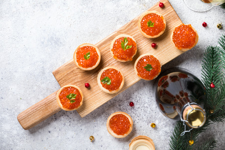 Christmas and New Year holidays composition. Red Salmon Caviar in wooden bowl, Tartlets Festive Appetizer and champagne on  gray background.Copy space for Text.の写真素材