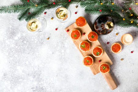 Christmas and New Year holidays composition. Red Salmon Caviar in wooden bowl, Tartlets Festive Appetizer and champagne on  gray background.Copy space for Text.の写真素材
