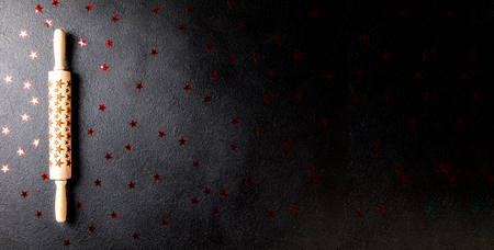 Rolling pin with a pattern in the form of stars on a black board. Baking Background .Preparation for cooking Food. Concept for Menu, Recipe, Ingredient. Copy space for Text.Bannerの写真素材