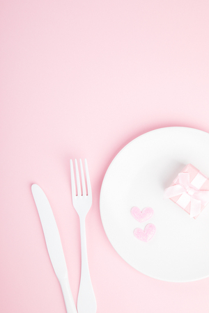 Festive table setting for Valentine's Day with fork, knife and hearts  on pink pastel background.Romantic dinner. Space for text. Top view.の写真素材