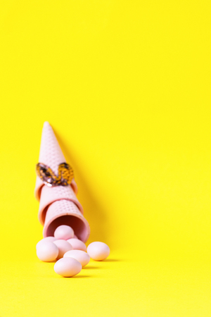 Happy Easter background  with Easter eggs.Wafer ice cream cone  light pink colors on yellow Paper. Creative Concept .Copy space for Text.の写真素材