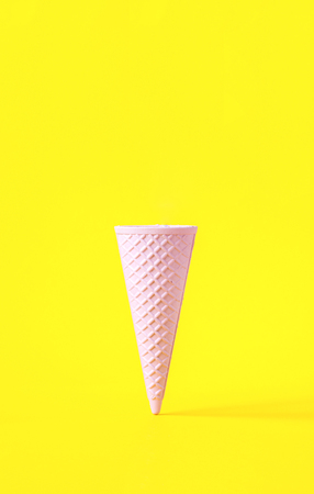Wafer ice cream cone  light pink colors on yellow background. Minimalistic concept. Idea creative.Copy space for Text.の写真素材