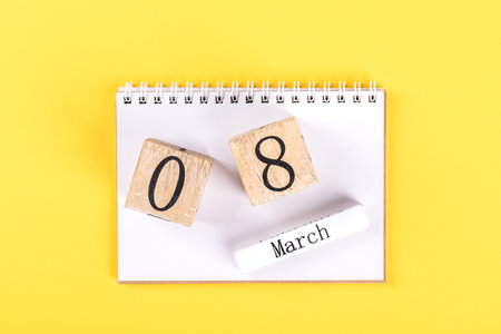 Wooden block calendar International of March 8 on a bright yellow background. Womens Day, is...