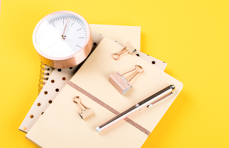 Notebook, pen and alarm clock on yellowの写真素材