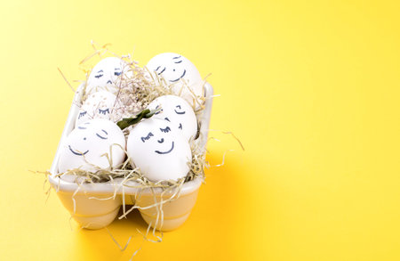 Easter holiday concept with cute handmade eggs.Eggs with funny faces in the package on a bright...