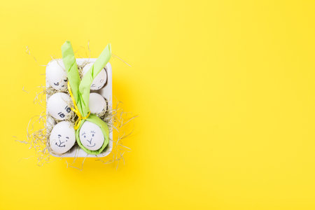 Easter holiday concept with cute handmade eggs.Eggs with funny faces in the package on a bright...