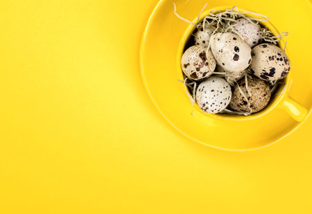 Easter holiday concept .Quail eggs in a yellow mug on a bright background.Traditional decoration a...