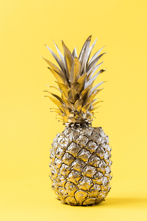 Creative layout made gold pineapple on brightly yellow background.Minimal style.  Tropical Food concept.Summer Idea .Copy space for Text.の写真素材