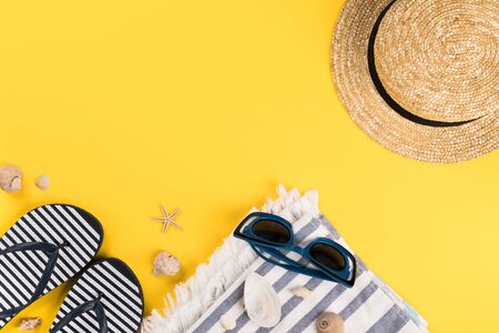 Beach accessories on yellow background. Flip flops,Straw Woman's Hat,Sun Glasses, towel.Summer vacation concept.Travel mood to the sea.Flat lay.の写真素材