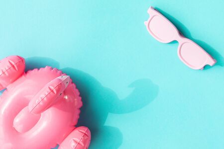 Beach accessories on blue background. Pink inflatable flamingo and white glasses.Summer vacation. Creative concept.Travel mood to the sea.Harsh sunlight shadow.Flat lay.の写真素材