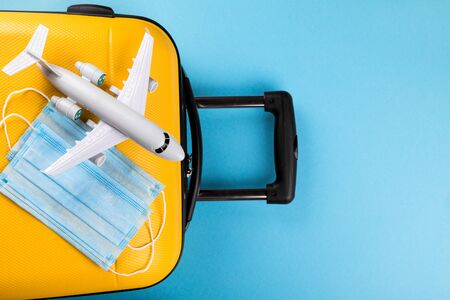 Yellow suitcase with traveler accessories on a blue background.Travel concept under the conditions of Coronavirus 2019-nCov.Concept protect the world from infection and spread of the virus.Pandemic.Personal protective equipment protection.Flat layの写真素材