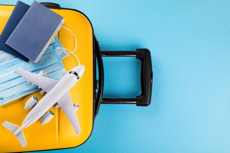 Yellow suitcase with traveler accessories on a blue background.Travel concept under the conditions of Coronavirus 2019-nCov.Concept protect the world from infection and spread of the virus.Pandemic.Personal protective equipment protection.Flat layの写真素材