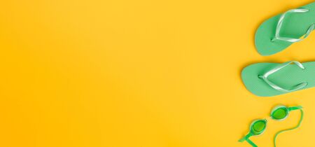 Beach accessories on yellow background. Flip flops, swimming mask, towel.Summer vacation concept.Travel mood to the sea.Banner.Flat lay.の写真素材