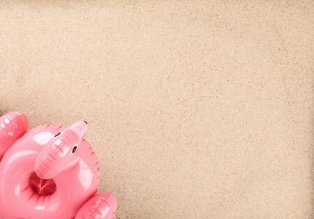 Inflatable Flamingo on a sand background.Trendy summer concept.Beach composition.Flat lay.Copy spaceの写真素材