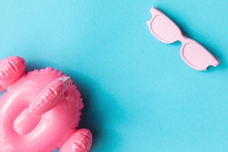 Beach accessories on blue background. Pink inflatable flamingo and white glasses.Summer vacation. Creative concept.Travel mood to the sea.Harsh sunlight shadow.Flat lay.の写真素材