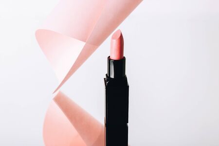 One pink lipstick in black tube and pink paper roll on light gray backgroundの写真素材