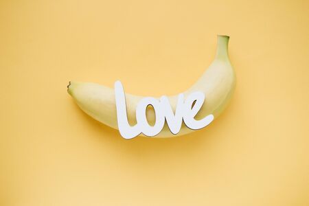 Word LOVE and one banana on yellow background, top viewの写真素材