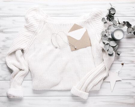 Cozy background. White sweater, postcard and candle on wooden backgroundの写真素材