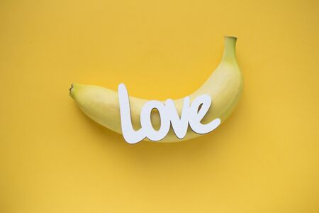 Word LOVE and one banana on yellow background, top viewの写真素材